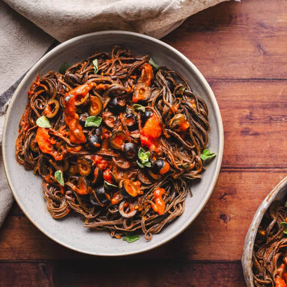 A bowl of tasty black soybean with tomato sauce and olives. 